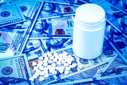 Heart-shaped pills on the background of hundred-dollar bills. The concept of the expensive cost of healthcare or financing medicine. White medicine bottle with copy space for text.