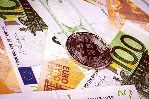 Euro bills and metal souvenir bitcoin. The concept of electronic money and commerce. Cryptocurrency and cash.