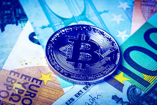 Euro bills and metal souvenir bitcoin. The concept of electronic money and commerce. Cryptocurrency and cash.