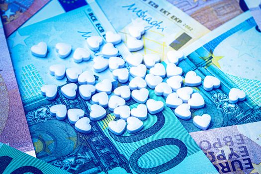 Heart-shape pills on the background of euro bills. The concept of the expensive cost of healthcare or financing medicine.