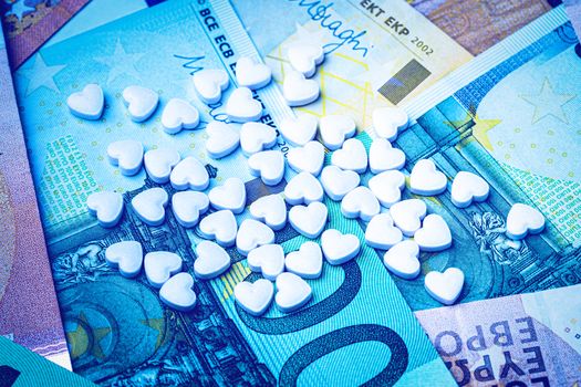 Heart-shape pills on the background of euro bills. The concept of the expensive cost of healthcare or financing medicine.