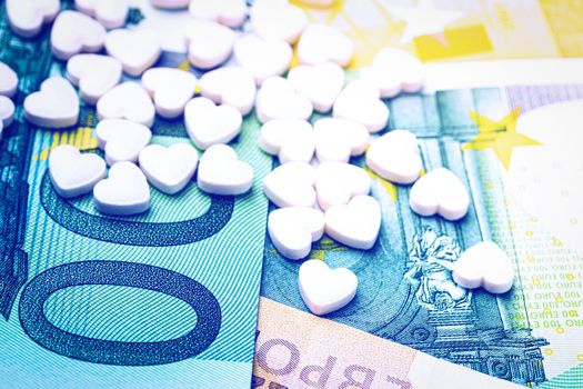 Heart-shape pills on the background of euro bills. The concept of the expensive cost of healthcare or financing medicine.