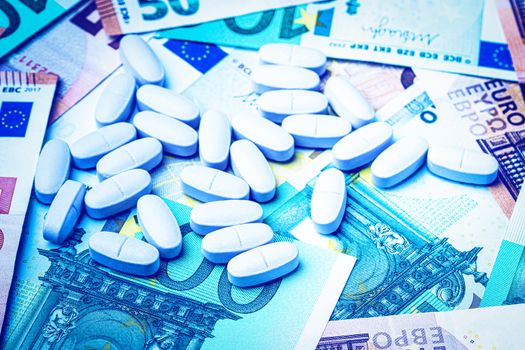 White pills on the background of euro bills. The concept of the expensive cost of healthcare or financing medicine.