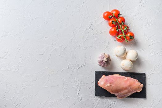 Raw chicken breast on stone board over white background