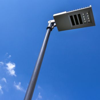 Modern street lamp against blue sky and clouds