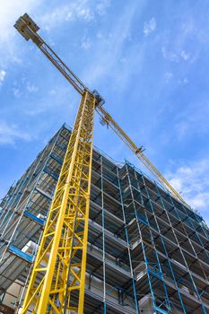 Construction site with yellow crane on sky background. Bottom view.