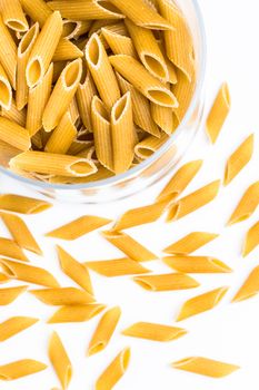 Italian dry pasta in the shape of pens in a glass bowl.