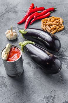 Aubergine penne ingredients eggplant pasta, pepper tomatoe sauce, on grey background side view