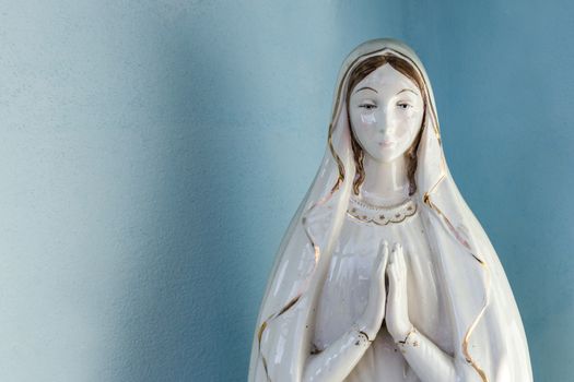 Our Lady vintage porcelain statue, in a light blue background.