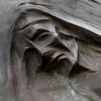 Detail of a mourning sculpture on a cemetery. (Religion, faith, suffering concept).