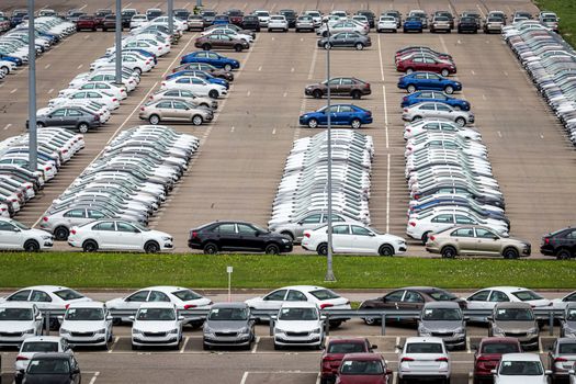 Rows of a new cars parked in a distribution center of a car factory. Top view to the parking in the open air.