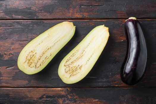 Ripe aubergine or eggplant half sliced on old wooden background top view