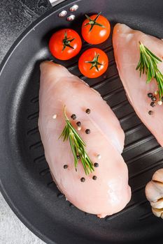 Raw organic chicken breastin grill pan on a grey background. Food preparation, top view close up