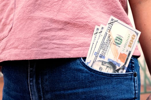 Many dollar 100 banknotes in a woman's front jean pocket