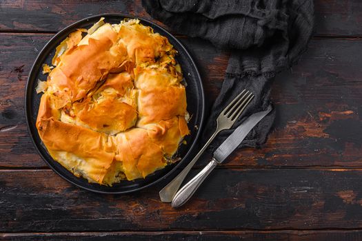 Homemade Greek spanakopita in on black plate filo spinach eggs feta top view on dark wooden background. Space for text