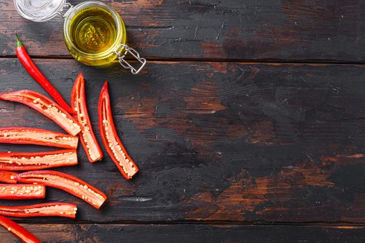 Ripe chili pepper sliced for making spicy olive oil over old dark wooden table top view space for text