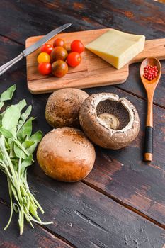 Portabello mushrooms ingredients for baking, cheddar cheese and sage on black background. Side view. High quality .