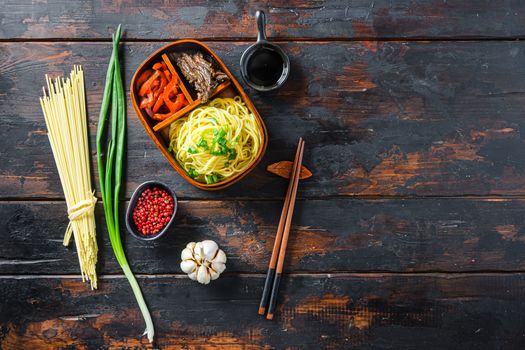 Homemade Bento pack lunch, grilled beef and noodles with ingredients top view dark wooden table space for text