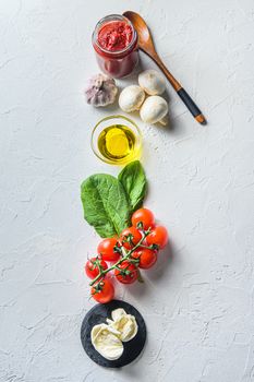 Pizza ingredients for cooking, tomatoes, oil, garlic, basil, sauce, mushroom on white background.