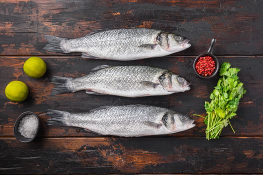 Seabass with spices and herbs ingredients on old fisherman dark wooden table top view.