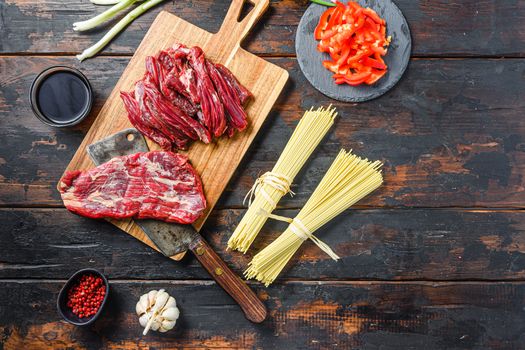 Cooking ingredients for Stir fry noodles with vegetables and beef . Machete steak and noodles on wooden background. Space for text