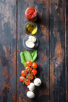 Raw pizza ingredients for cooking, tomatoes, oil, garlic, basil, sauce, mushroom on wood background.