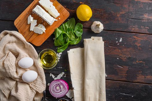 Greek spanakopita ingredients filo spinach eggs feta top view on dark wooden background space for text