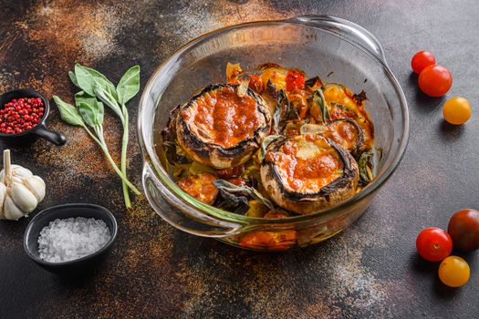 Portobello mushrooms,baked with cheddar cheese, cherry tomatoes and sage in glass pot on old rustic metall dark background side view