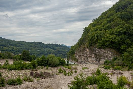 Cloudy summer landscape with a stone bed of the Ashe river