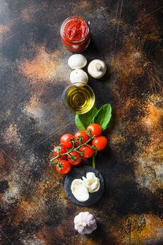 Food ingredients and spices for cooking, tomatoes, oil, garlic, basil, sauce, mushroom on dark background.