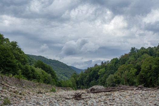 Cloudy summer landscape with a stone bed of the Ashe river