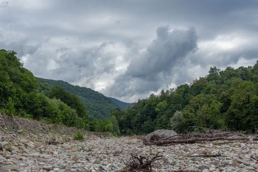 Cloudy summer landscape with a stone bed of the Ashe river