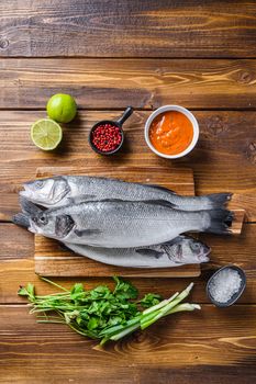 Couple sea bass with spices and herbs ingredients overwood table top view.