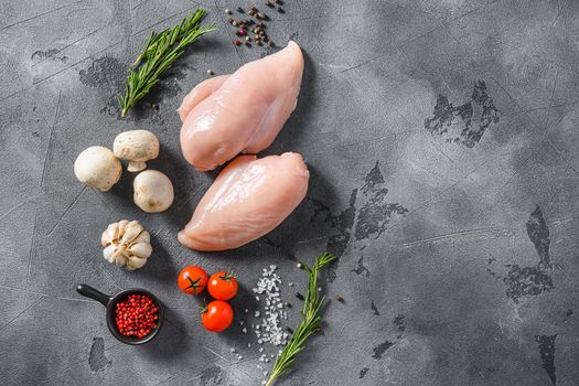 Organic chicken meat with garlic, pepper and rosemary on a grey concrete background top view space for text