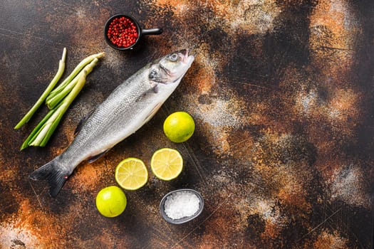 Raw seabass with spices and herbs ingredients over darc rustic background top view space for text