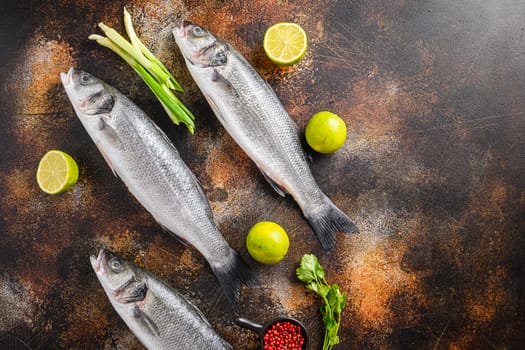 Set of raw sea bass with spices and herbs ingredients over darc rustic background top view space for text