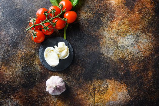 Raw pizza ingredients for cooking, tomatoes, oil, garlic, basil, sauce, mushroom on dark background.