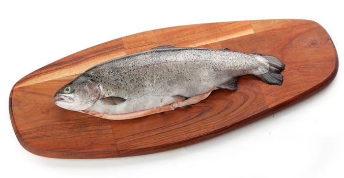 Idolated raw gutted trout on the brown wooden board 