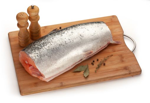 Piece of salmon with herbs and spices on the wooden board