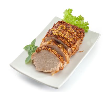 Baked pork with frebch mustard, basil and lettuce on the white plate