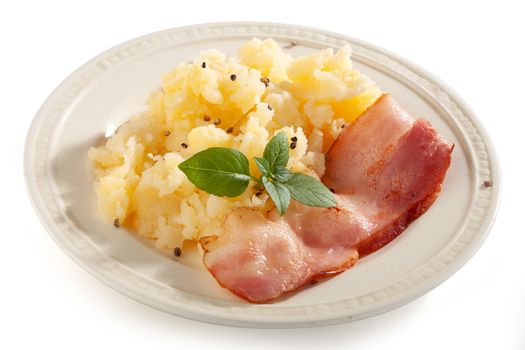 Mashed potatoes with bacon and green basil on the plate