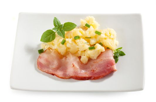 Mashed potatoes with bacon, basil and green onion on the white plate