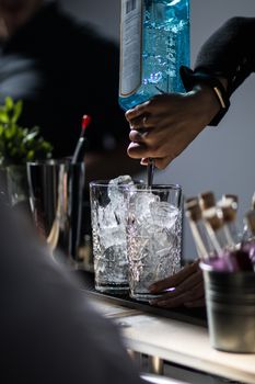 Cocktail making Barkeeper pouring gin. Mixing drinks on event. Bartender on cocktail party