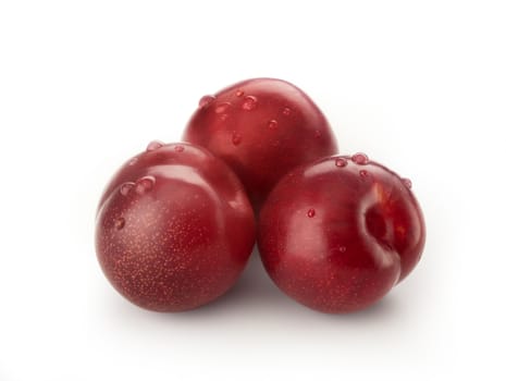 Three Isolated red plums with dew on the white background