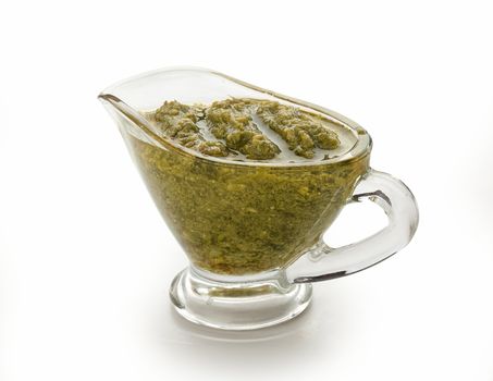 Pesto sauce in the gravy boat on the white