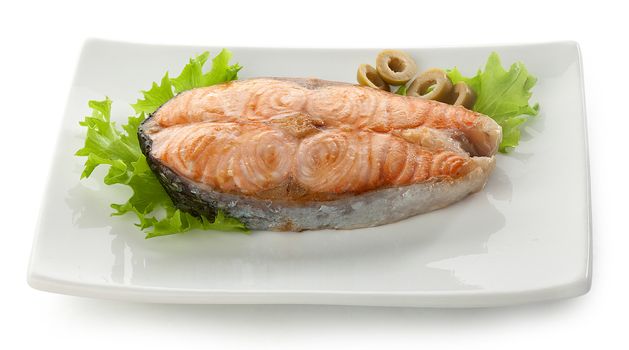 Baked steak of salmon with olives and fresh lettuce on the plate