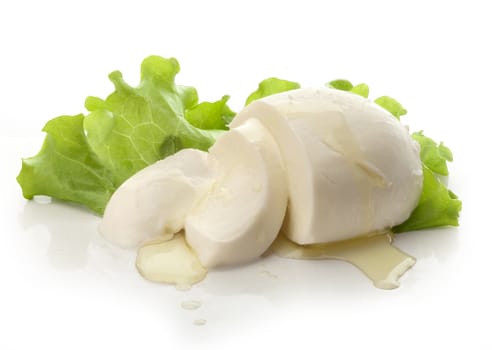 Sliced ball of mozzarella dressed by olive oil and green lettuce