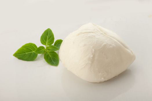 Whole ball of mozzarella with fresh greeen basil leaves