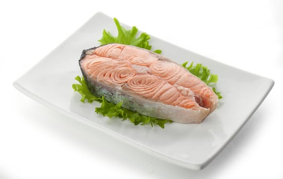 Steamed steak of salmon with fresh lettuce on the plate