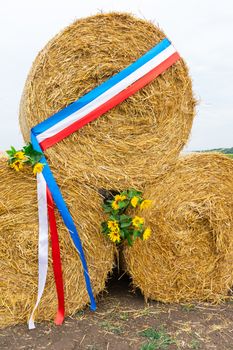 round bales of straw are stacked one by one with a ribbon of the French flag